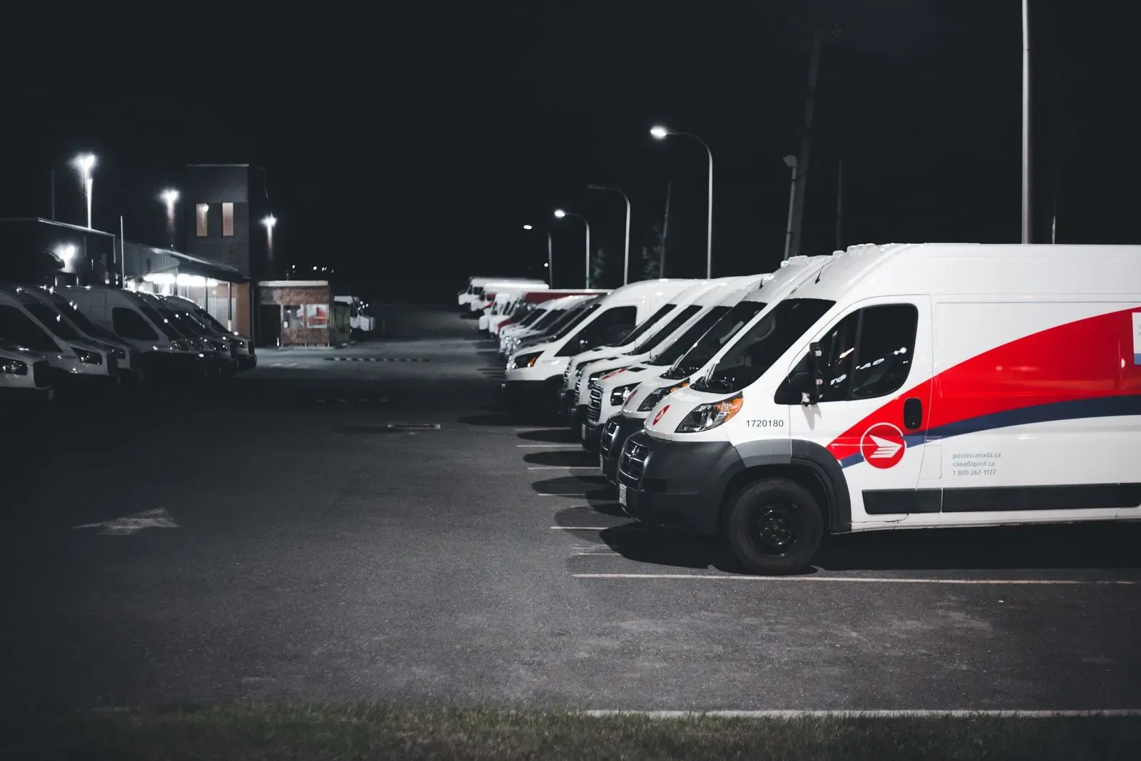 Rząd firmowych aut dostawczych na parkingu bazy — zdjęcie poglądowe
